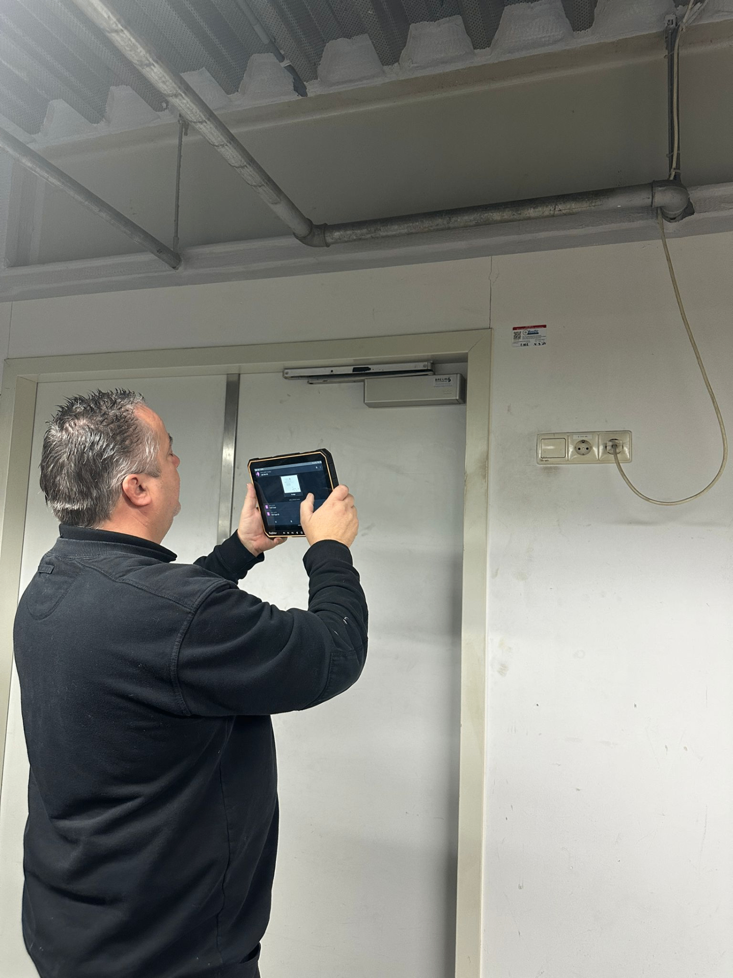 Monteur controleert installatie met tablet op locatie